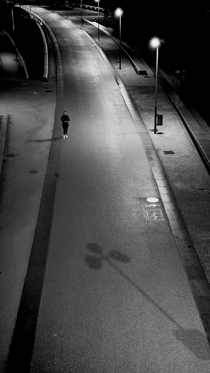 A lone runner on a dimly lit, empty urban path at night.
